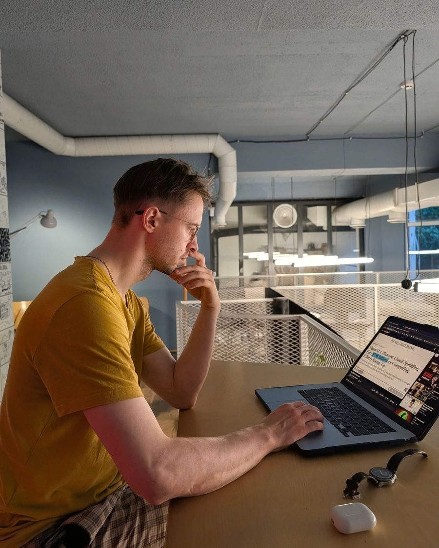Igor Shatsev at a laptop in a co-working loft, chin in hand, reading a Wall Street Journal article on screen.